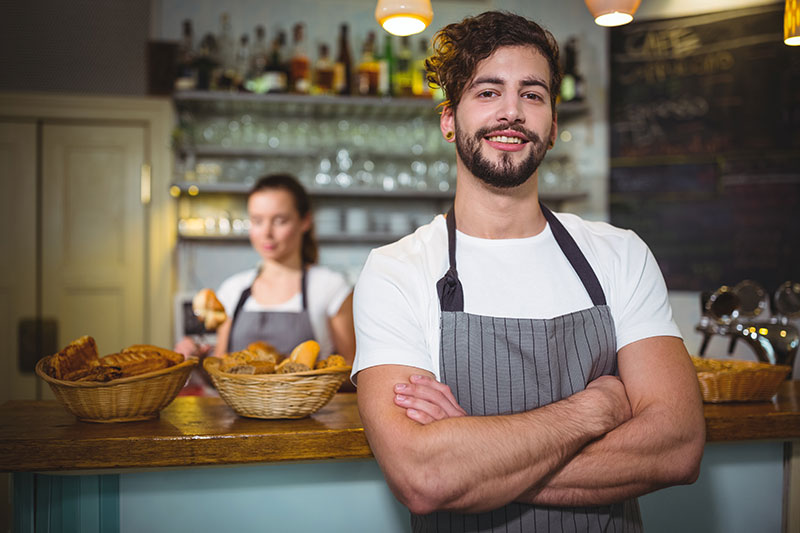 smiling-waiter-standing-with-arms-crossed-cafa-c